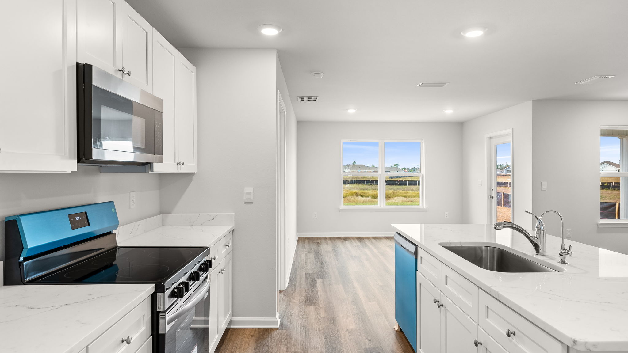 Kitchen with island and granite countertops with white cabinets and stainless-steel appliances.