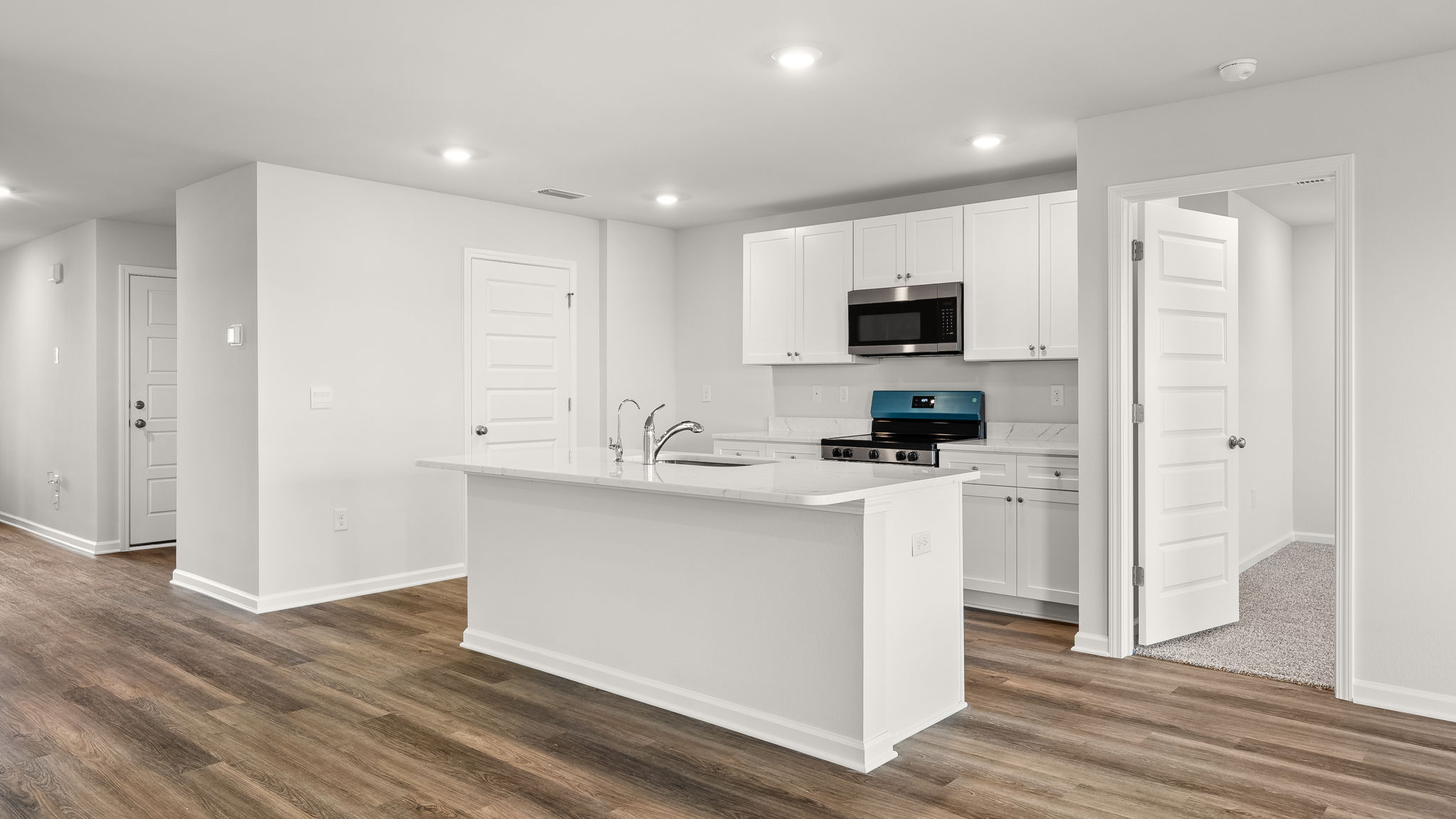 Kitchen with island and granite countertops with white cabinets and stainless-steel appliances.