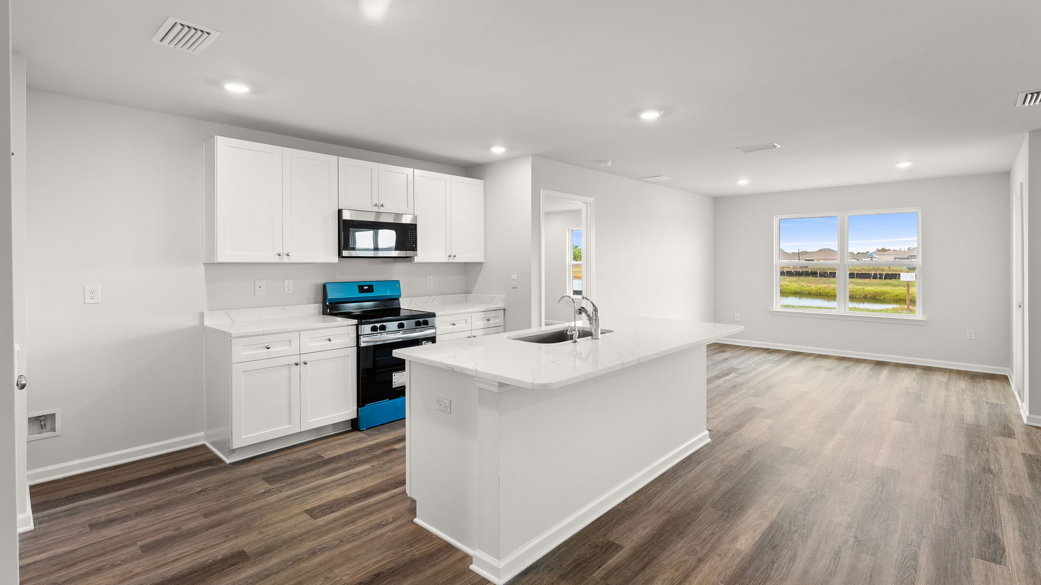 Kitchen with island and granite countertops with white cabinets and stainless-steel appliances.