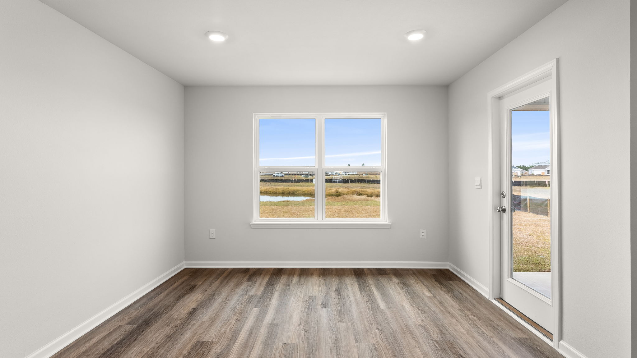 Dining area with EVP flooring and windows next to back door.