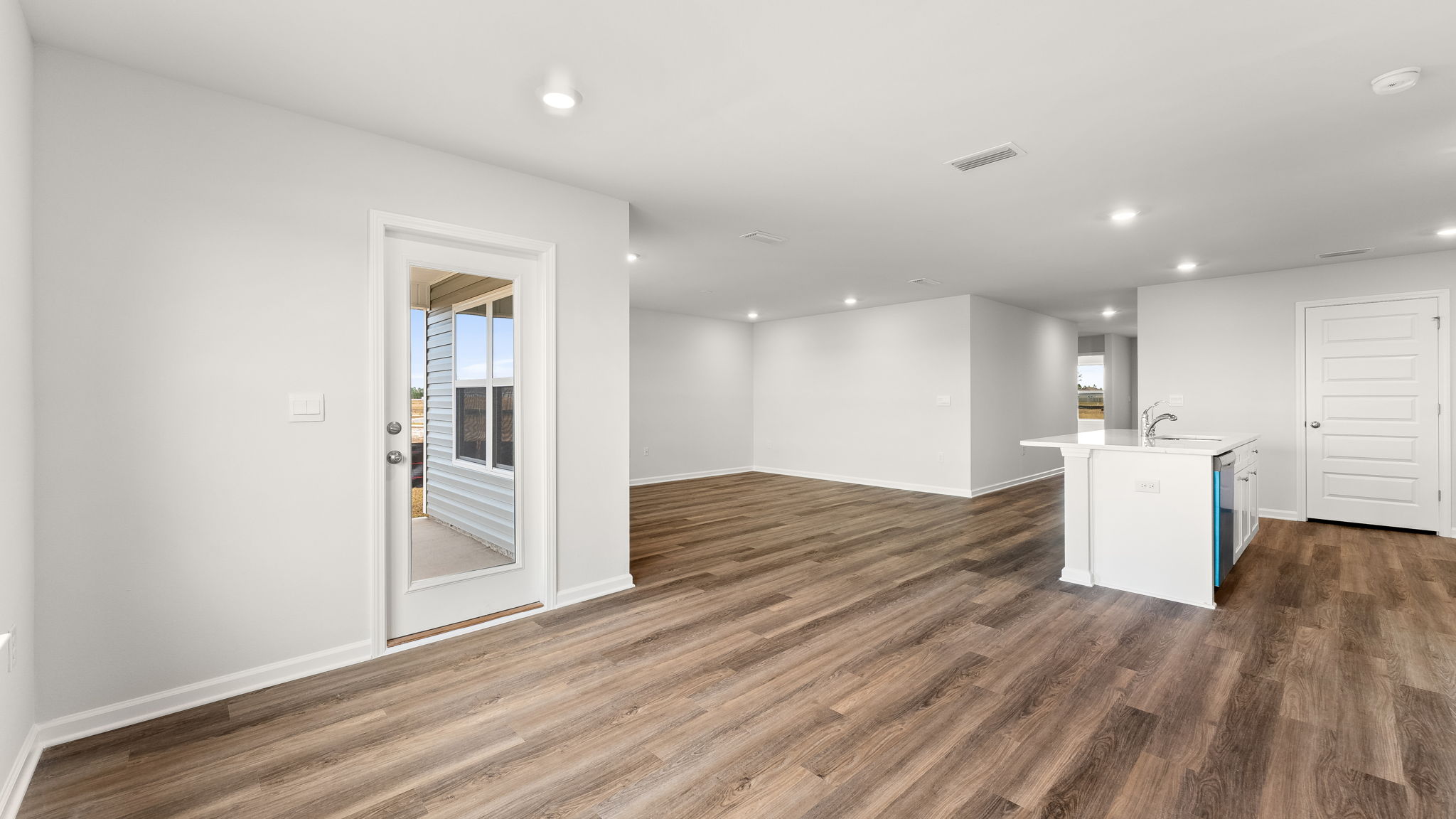 Dining area with EVP flooring and kitchen next to back door.