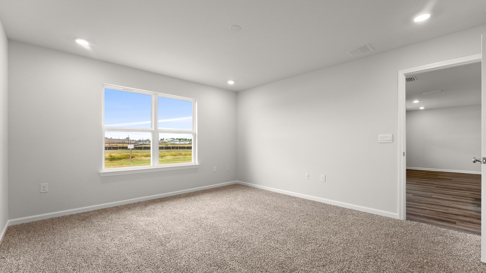Primary bedroom with carpet floors and living room entrance.