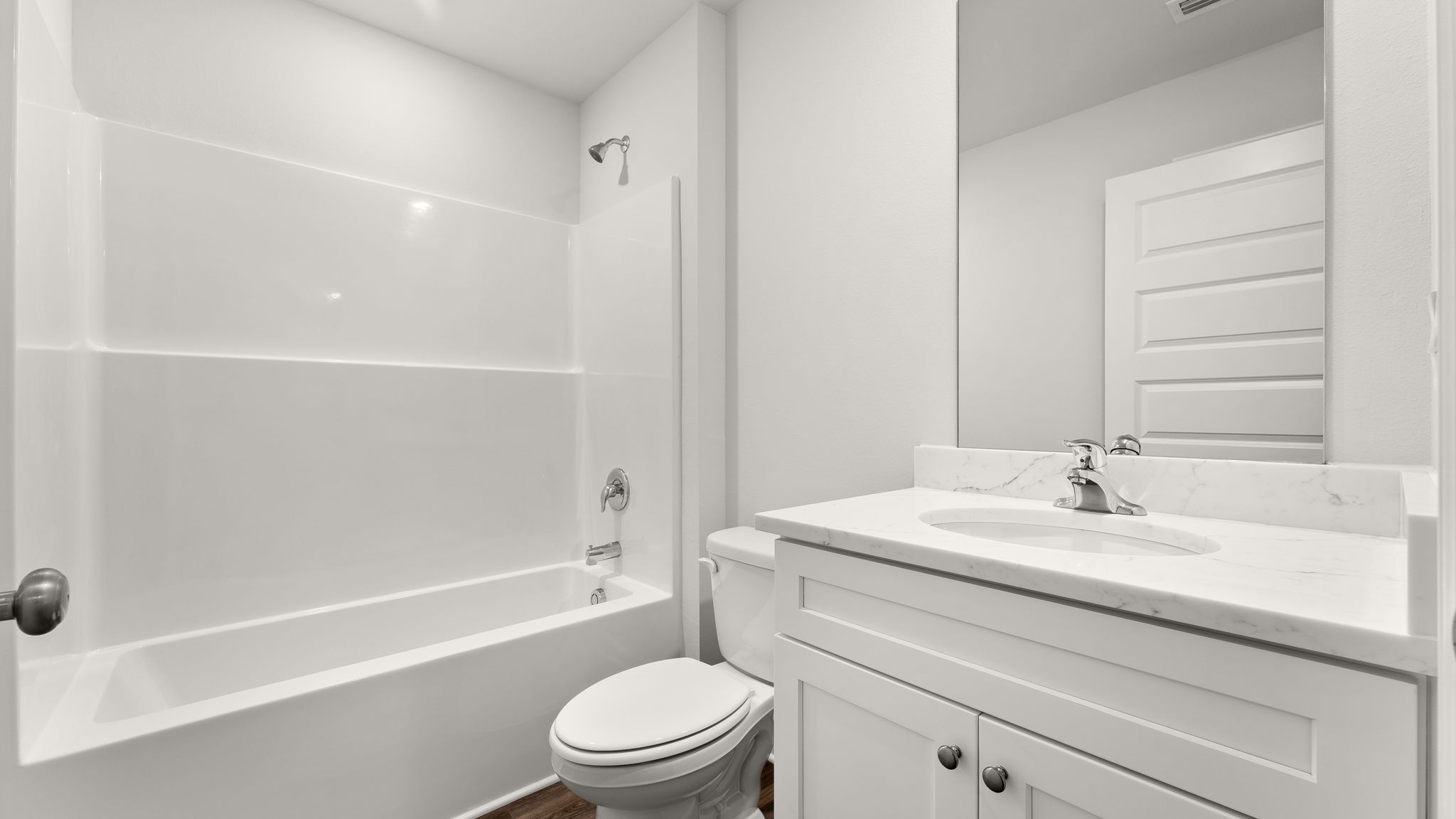 Bathroom with single vanity sink and quartz countertops with white cabinets and EVP flooring and shower and toilet.