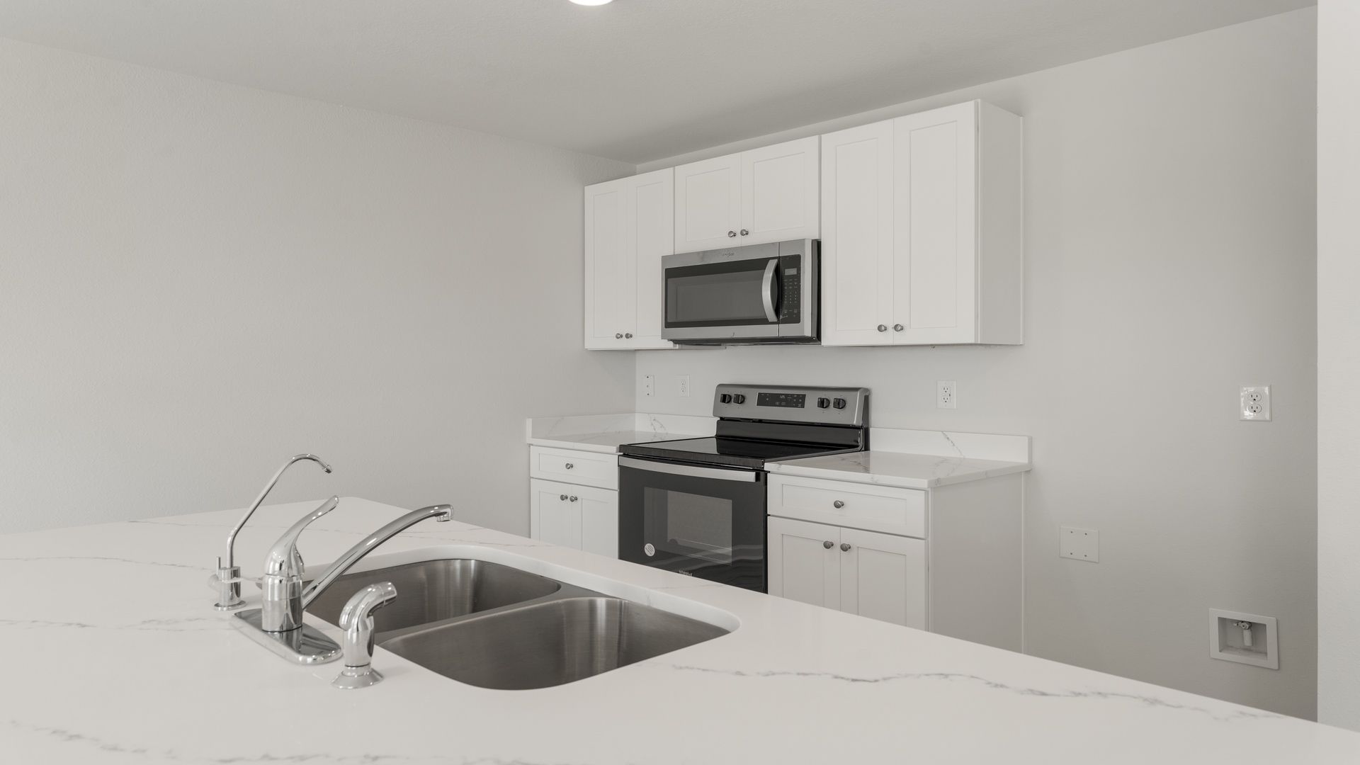 Kitchen island with quartz countertops and stainless-steel appliances.