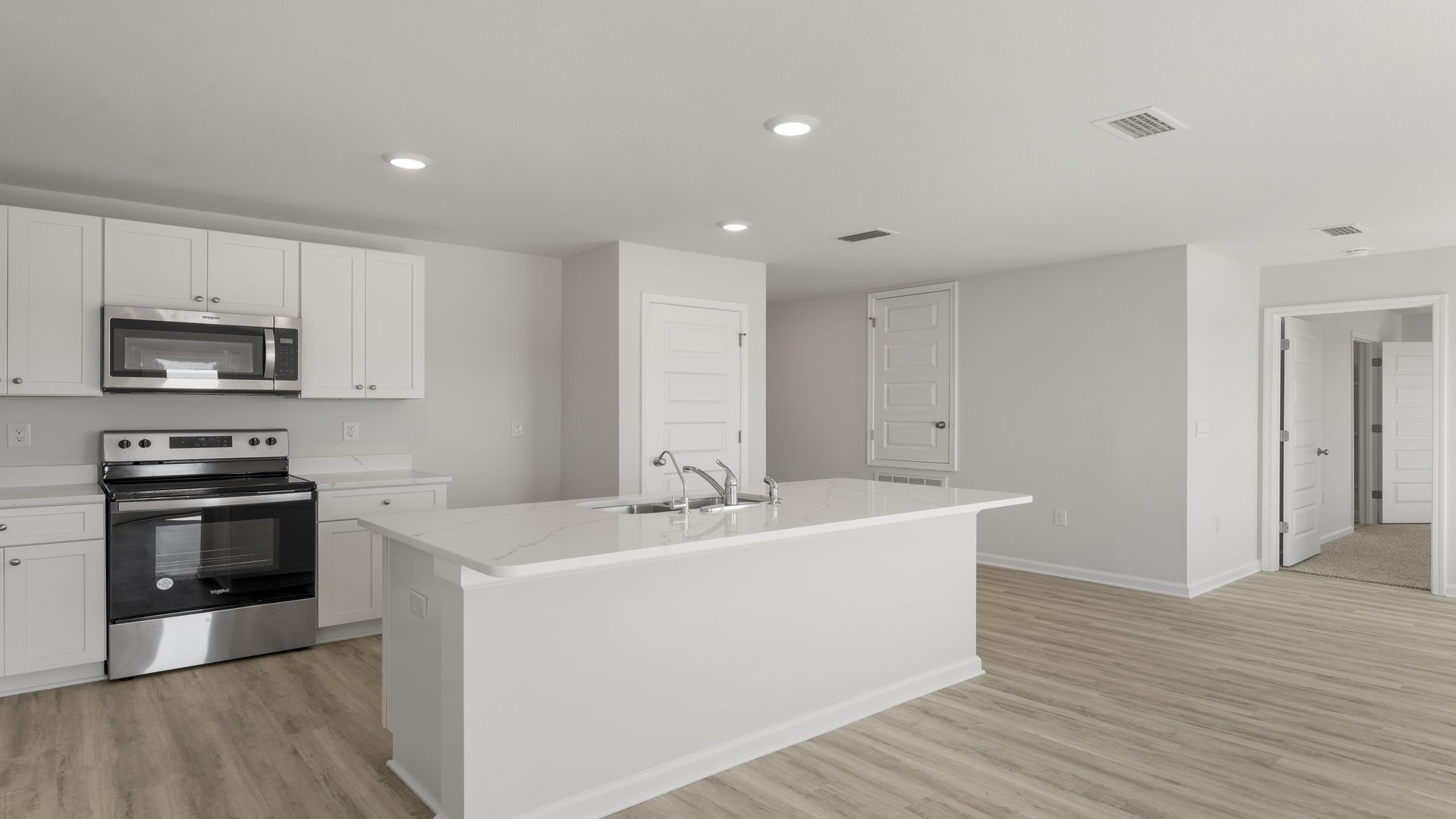 Kitchen island with quartz countertops and stainless-steel appliances and pantry.