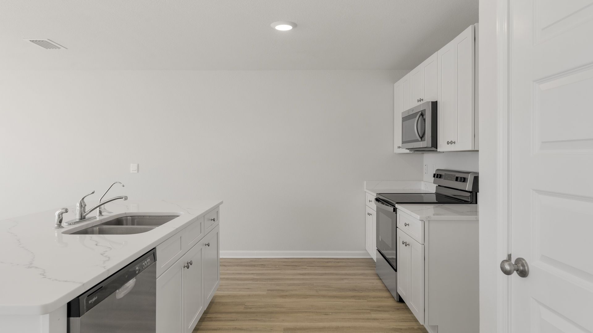 Kitchen island with quartz countertops and stainless-steel appliances and pantry.