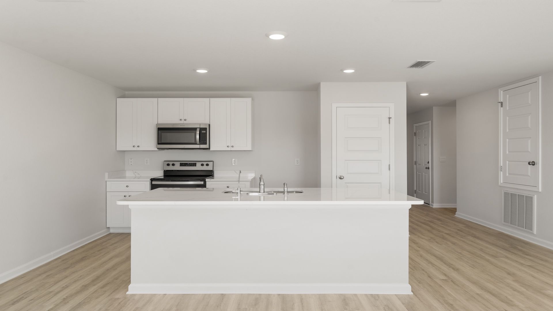 Kitchen island with quartz countertops and stainless-steel appliances and pantry.