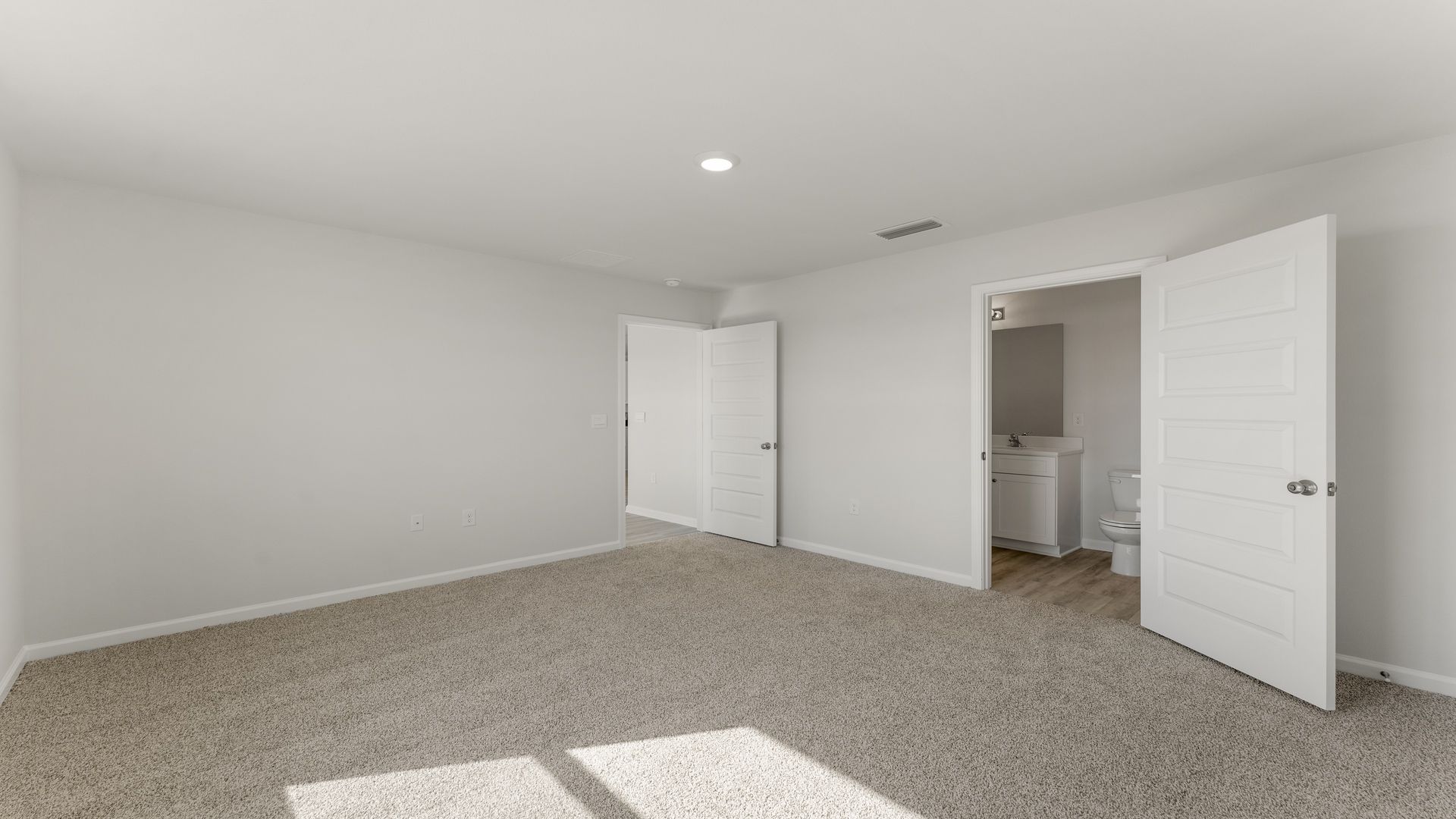 Primary bedroom with carpet floors and bathroom door.