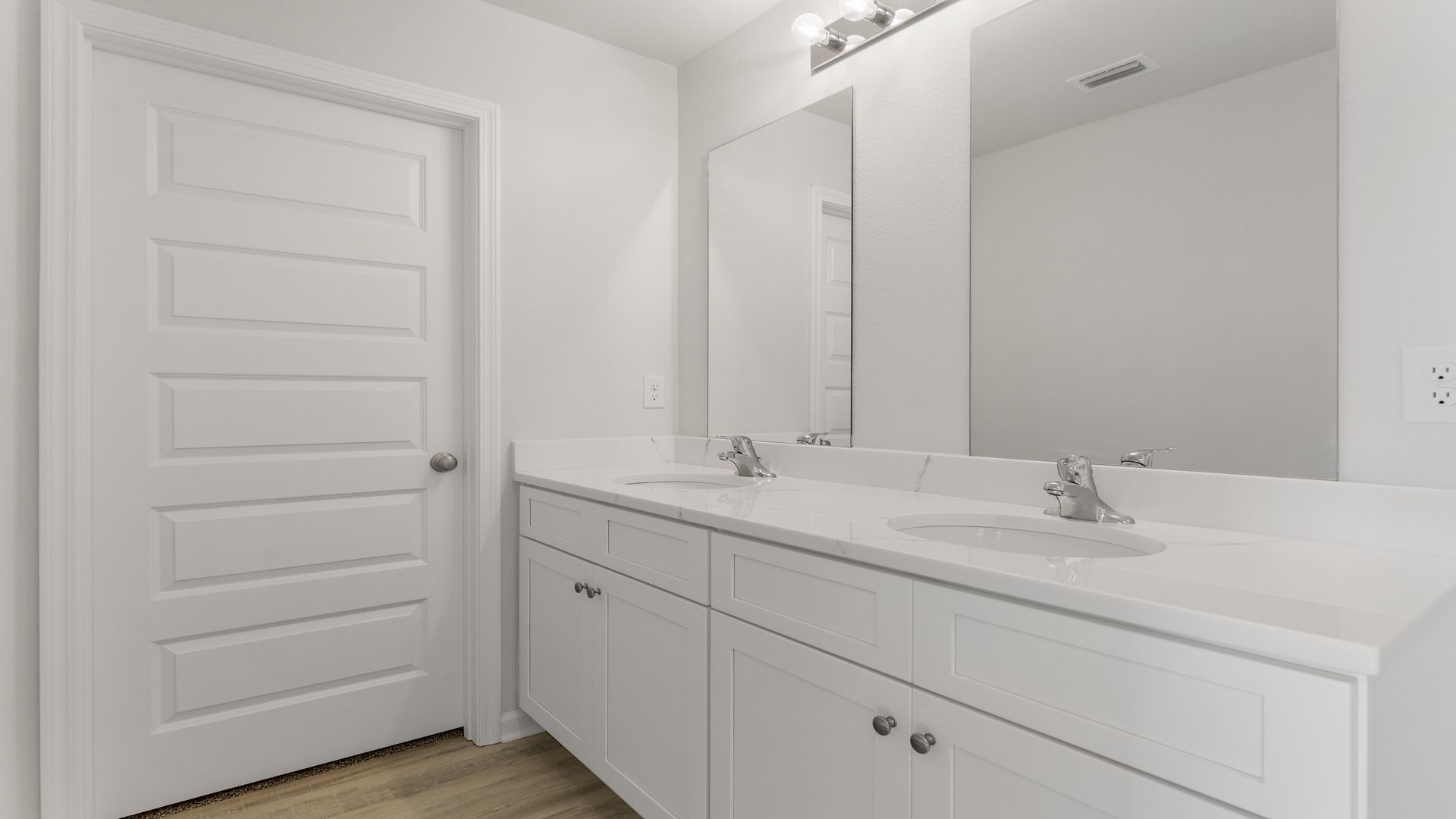 Primary bathroom with double vanity and quartz countertops.