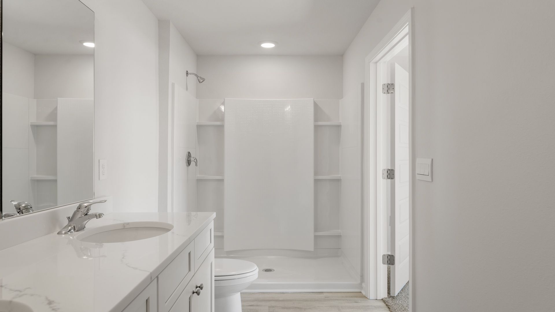 Primary bathroom with double vanity and quartz countertops and toilet and shower.