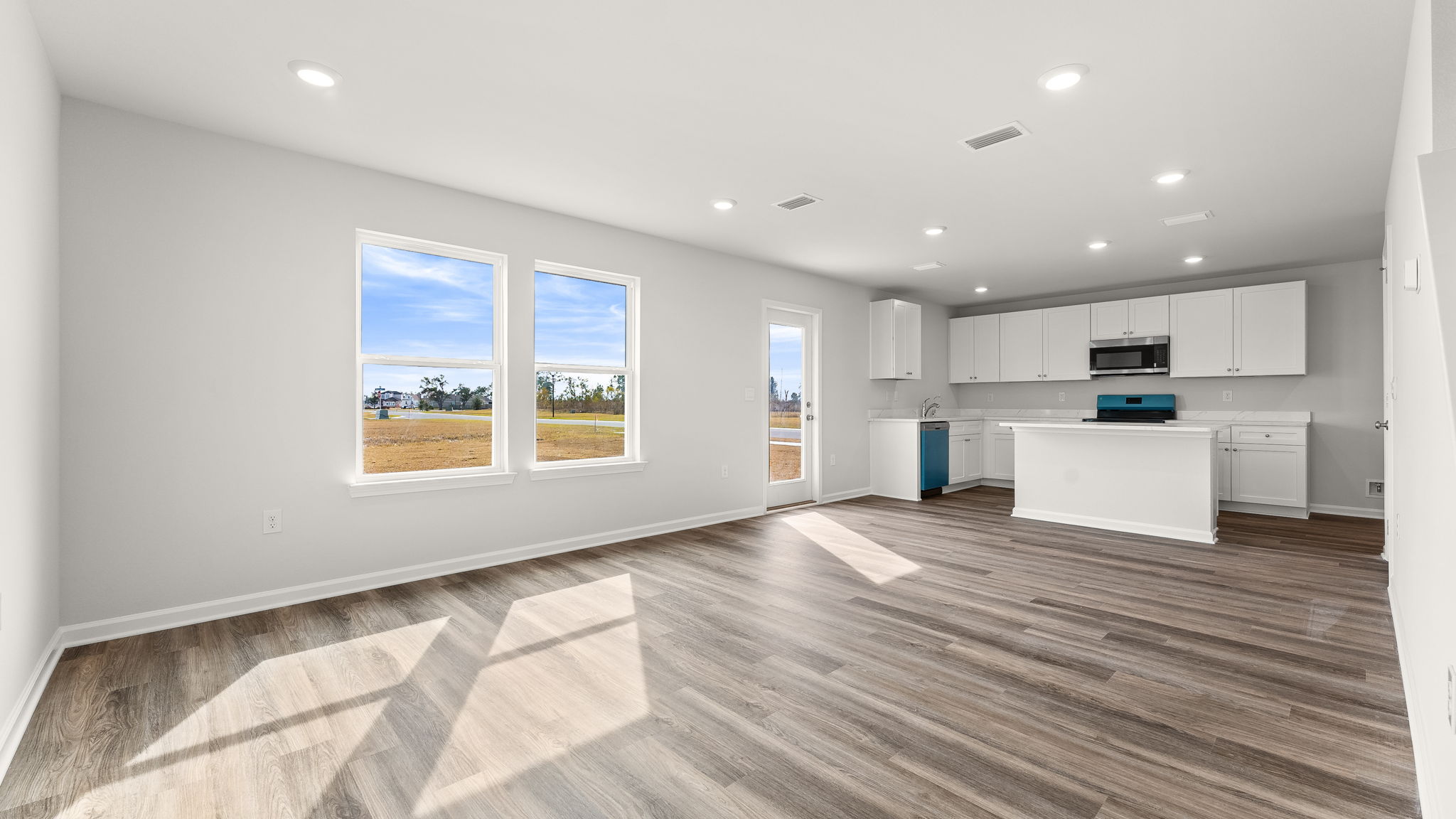 Living room and kitchen with EVP flooring and windows and back door.