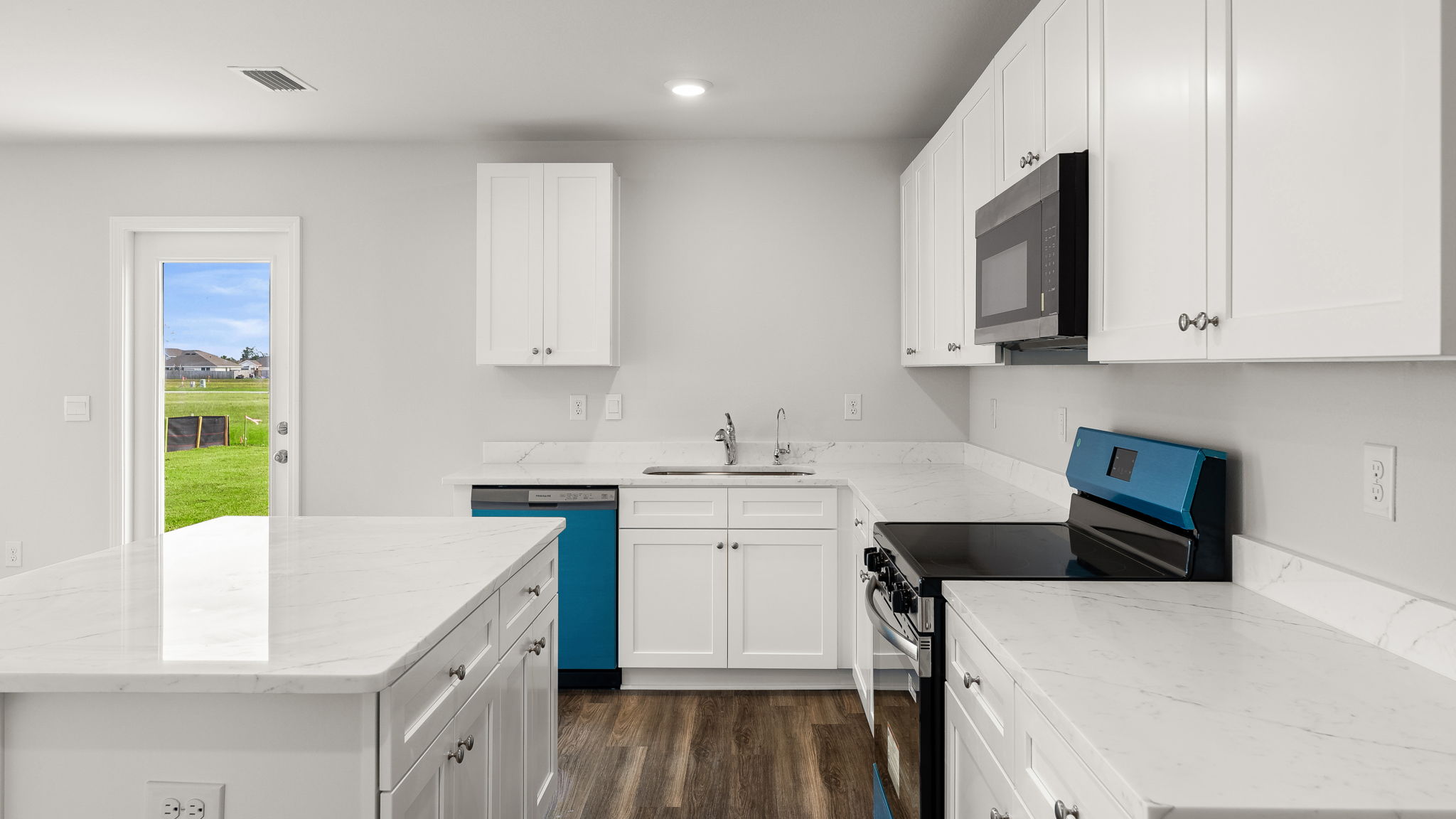 Kitchen with island and quartz countertops with white cabinets and stainless-steel appliances.