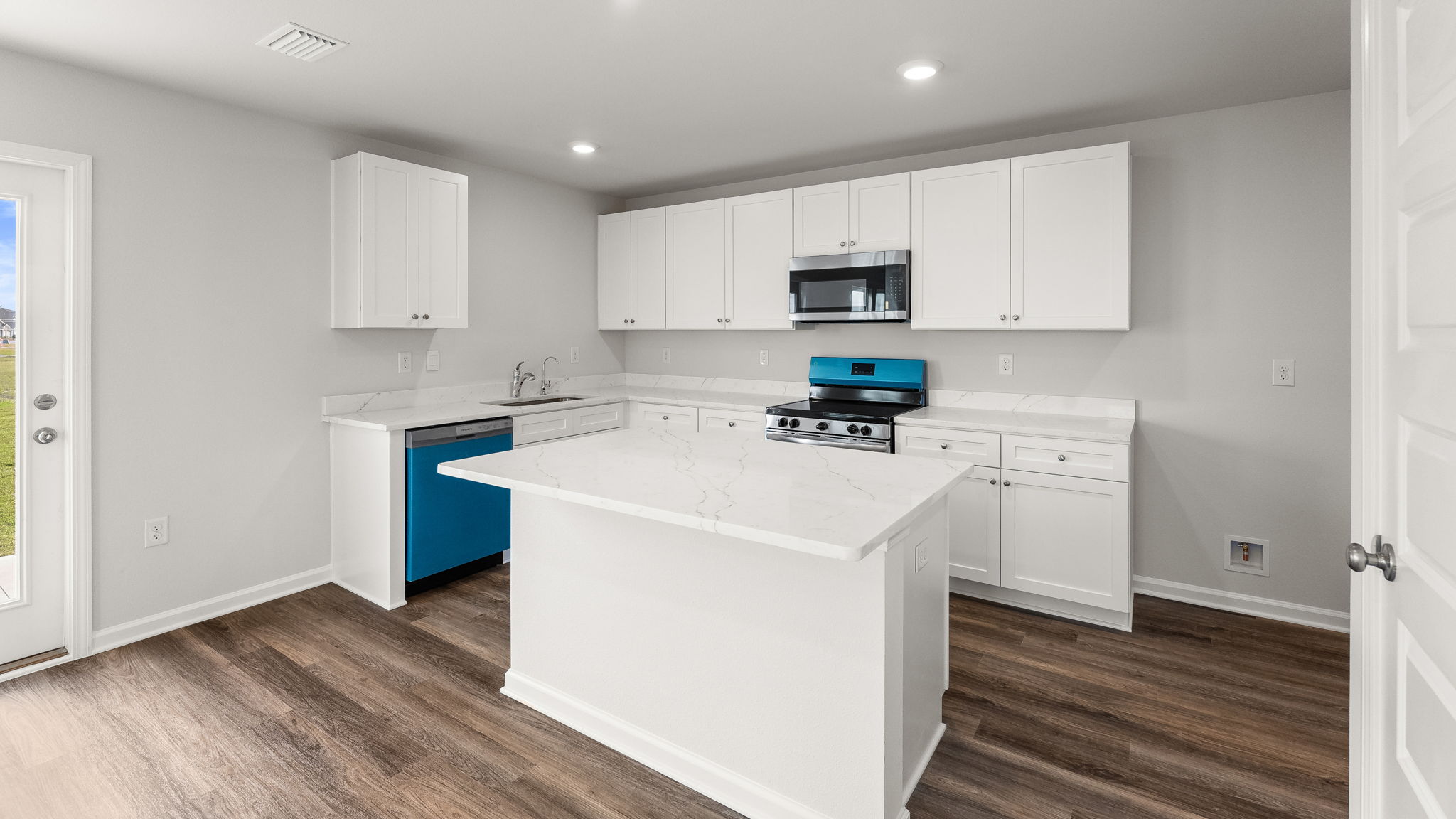 Kitchen with island and quartz countertops with white cabinets and stainless-steel appliances.