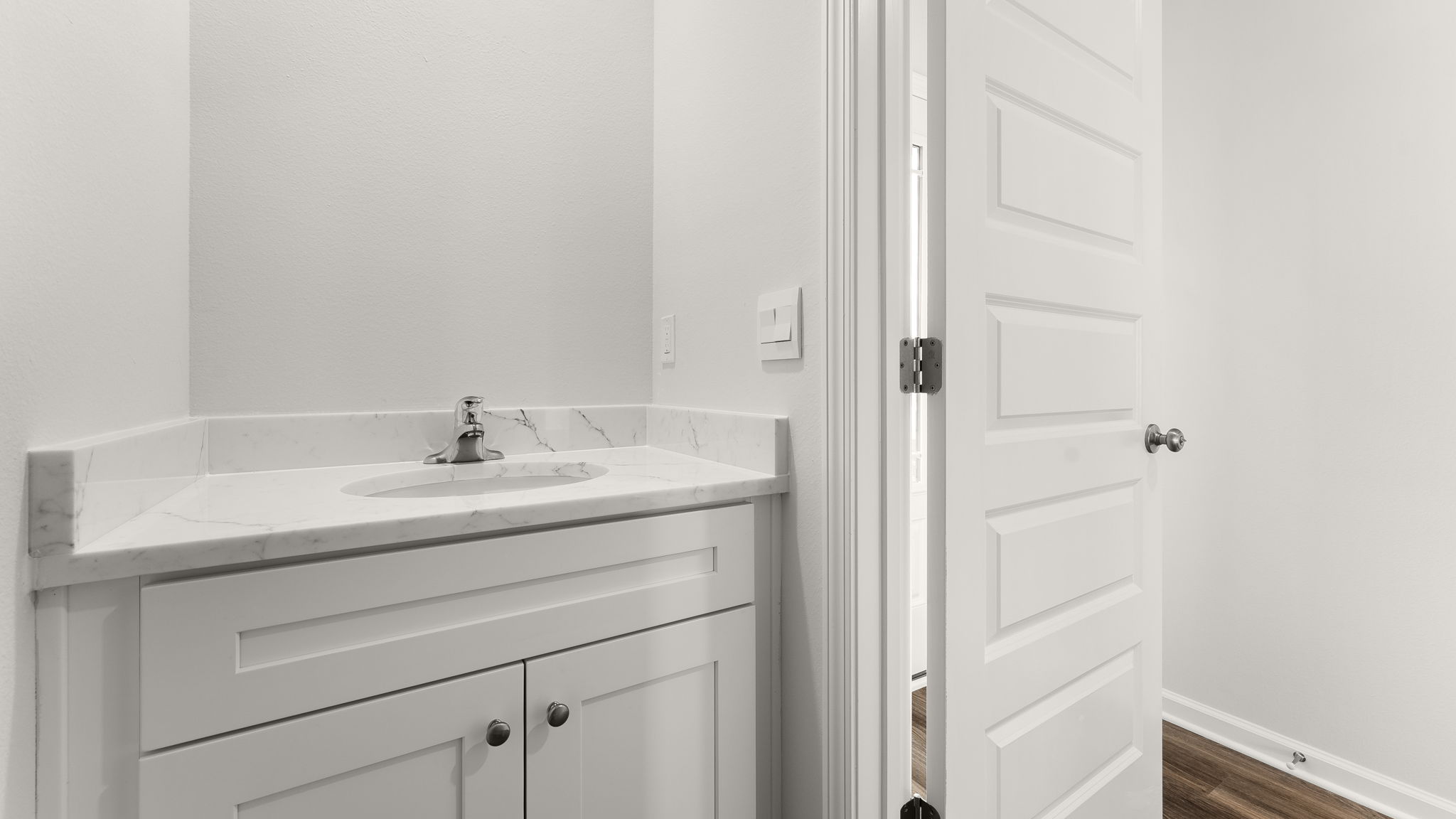 Half bathroom with white cabinets and quartz countertops.