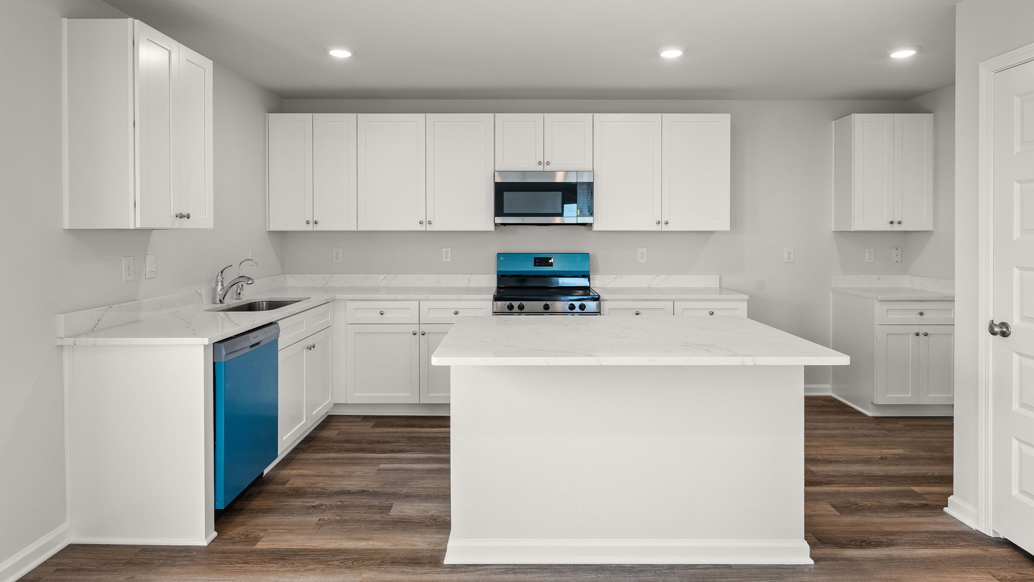 Kitchen with island and quartz countertops with white cabinets and stainless-steel appliances.