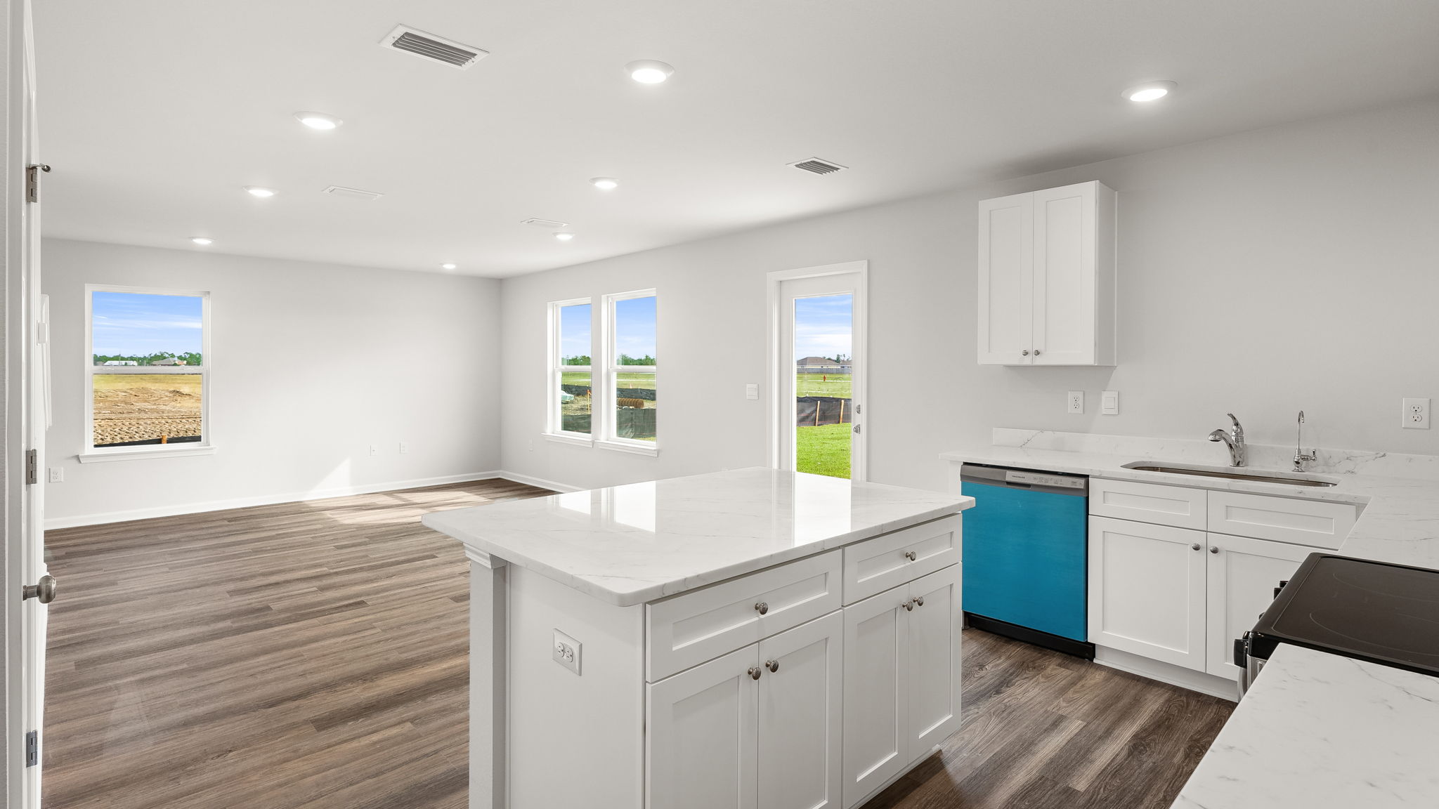 Kitchen with island and quartz countertops with white cabinets and stainless-steel appliances.