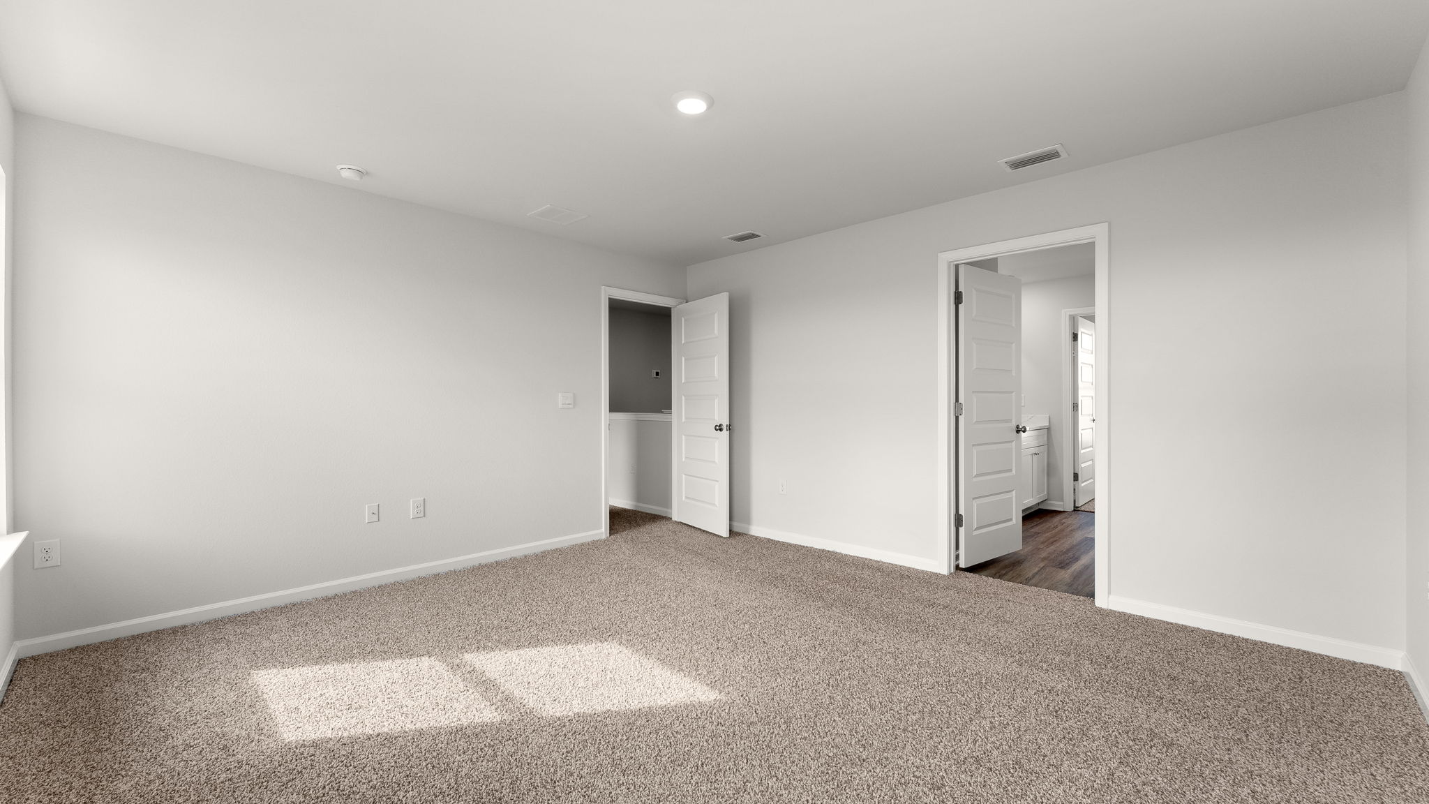 Primary bedroom with carpet floors and bathroom entrance.