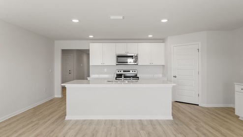 Kitchen island with white cabinets and stainless-steel appliances and quartz countertops.