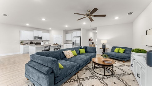 Open living room with ceiling fan and EVP flooring and kitchen.