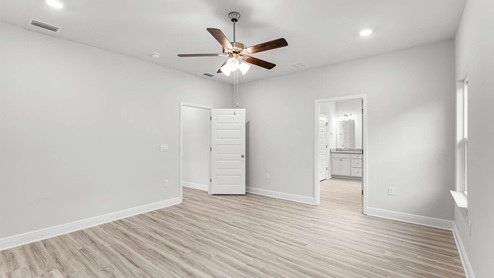 Primary bedroom with EVP flooring and ceiling fan and primary bathroom entrance.
