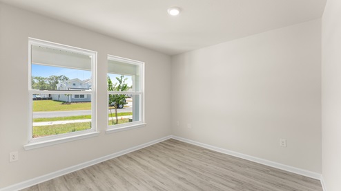 Bedroom with EVP flooring and two windows.