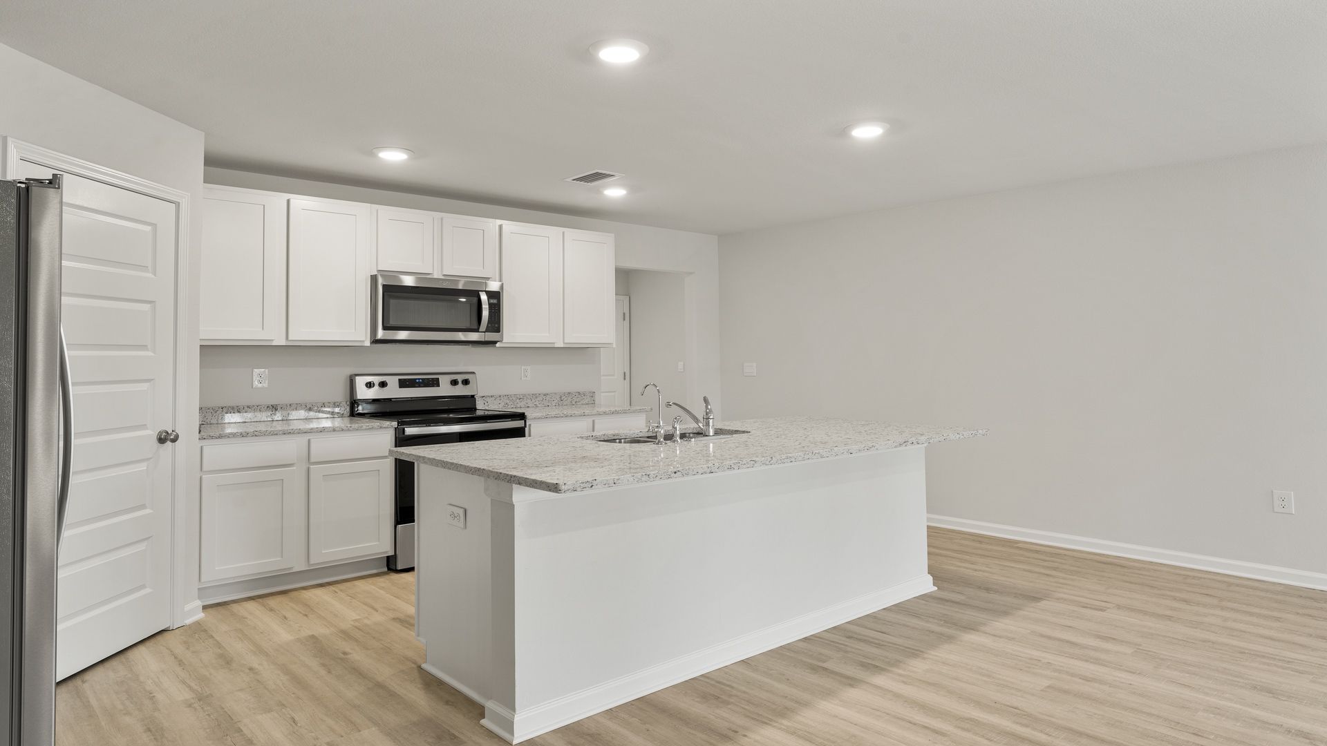 Kitchen with island and white cabinets and stainless-steel appliances and granite countertops and pantry.