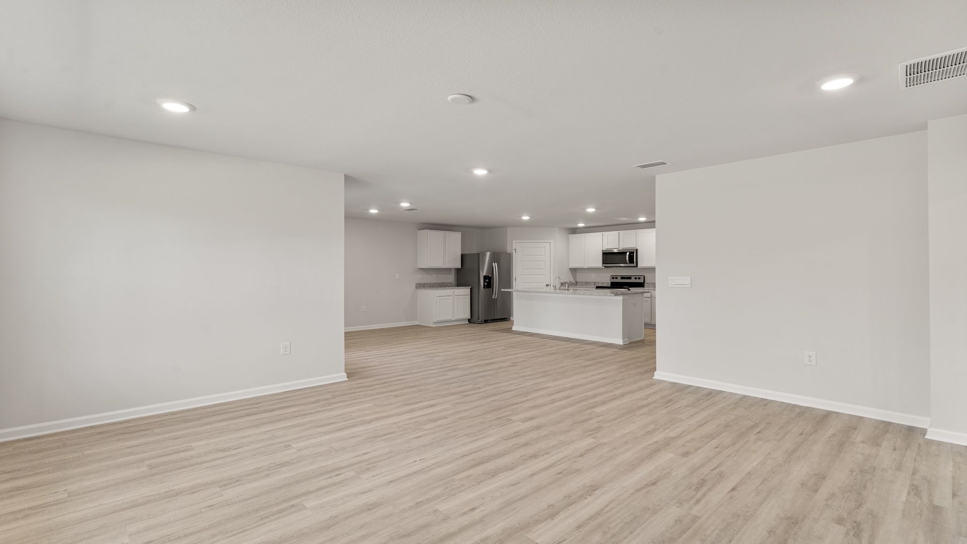 Open living room with EVP flooring looking into kitchen.