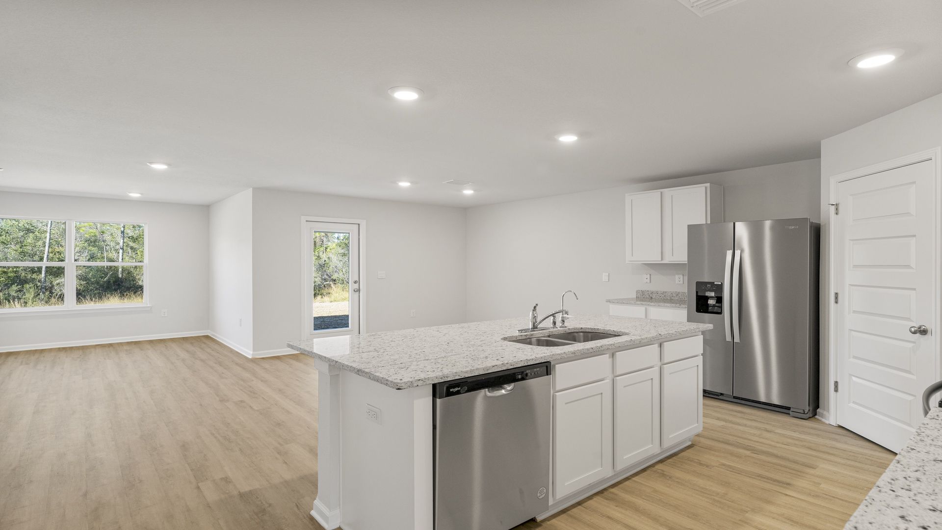 Kitchen island with white cabinets and stainless-steel appliances and granite countertops.