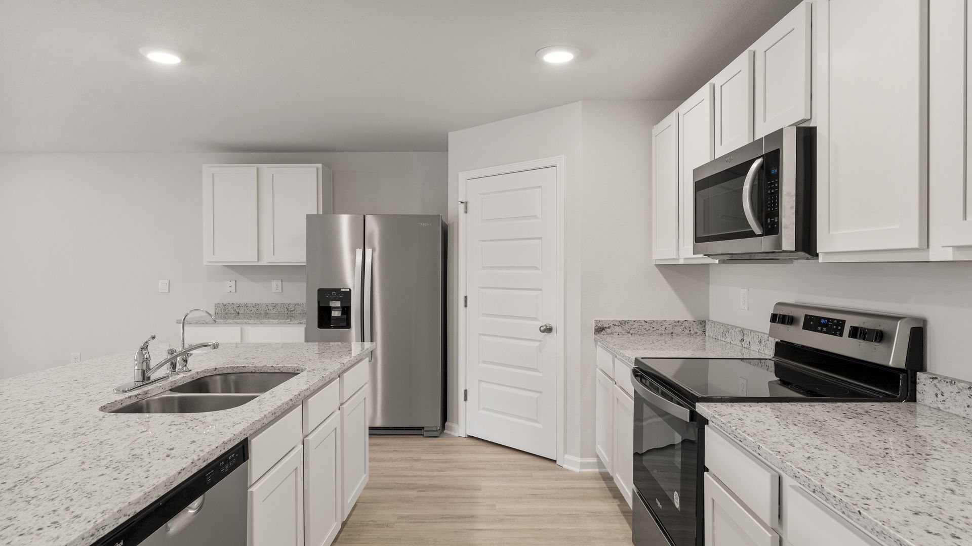 Kitchen with island and white cabinets and stainless-steel appliances and granite countertops and pantry.