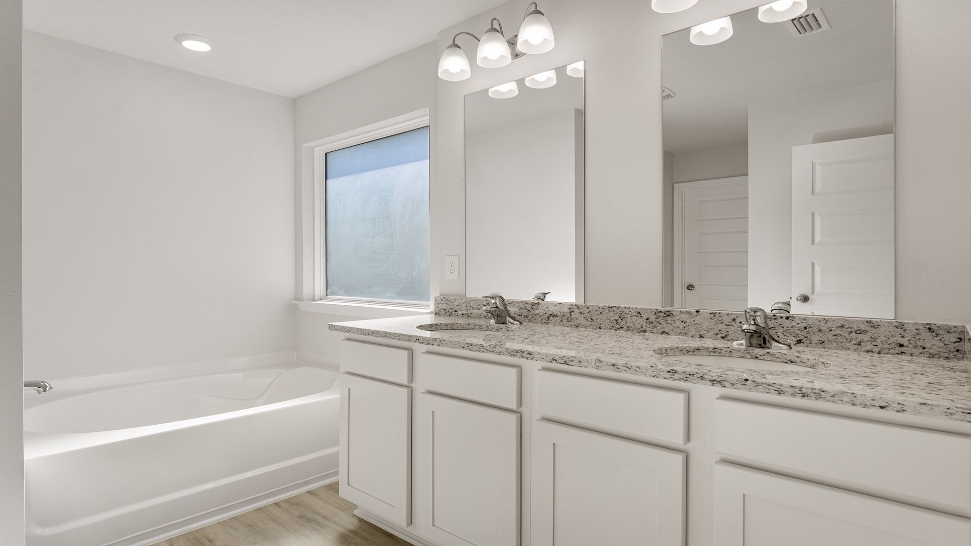 Primary bathroom with double vanity granite countertops and separate tub.