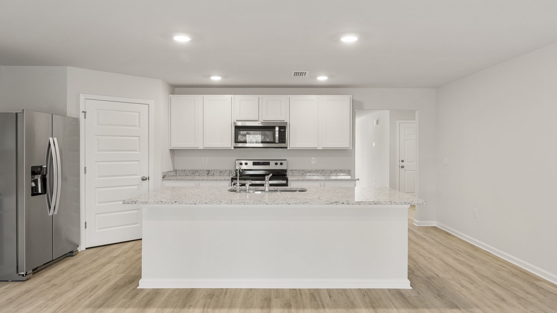 Kitchen with island and white cabinets and stainless-steel appliances and granite countertops and pantry.
