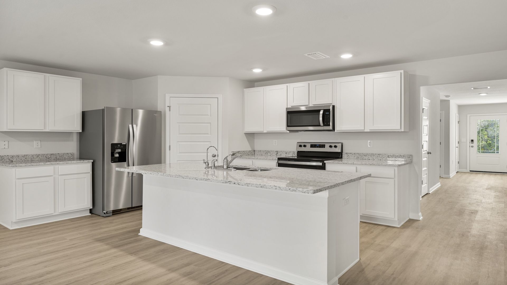 Kitchen with island and white cabinets and stainless-steel appliances and granite countertops and pantry.