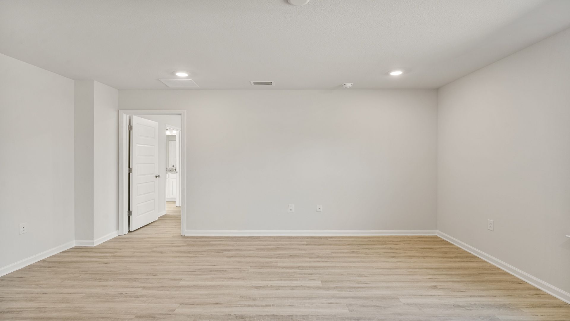 Open living room with EVP flooring and primary bedroom entrance.