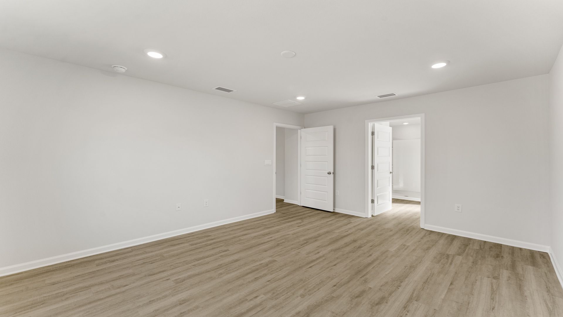 Primary bedroom with EVP flooring and primary bathroom entrance.