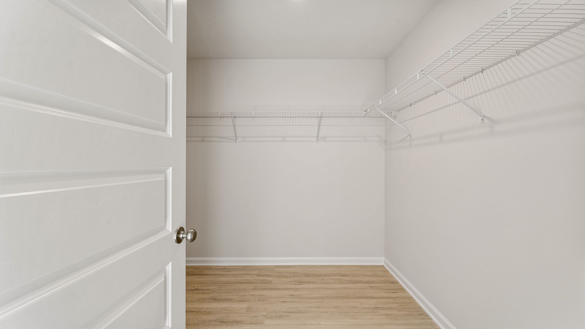 Primary bathroom walk-in closet with EVP flooring and ventilated shelving.