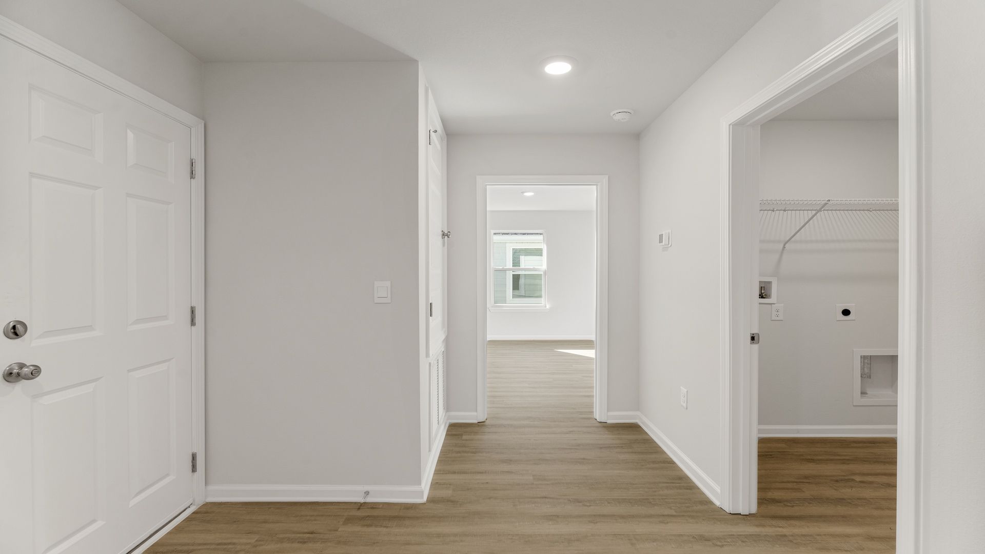 Hallway by garage entrance and bedroom and laundry room with EVP flooring.
