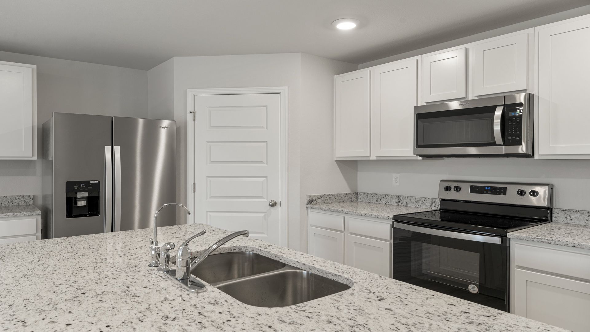 Kitchen with island and white cabinets and stainless-steel appliances and granite countertops and pantry.