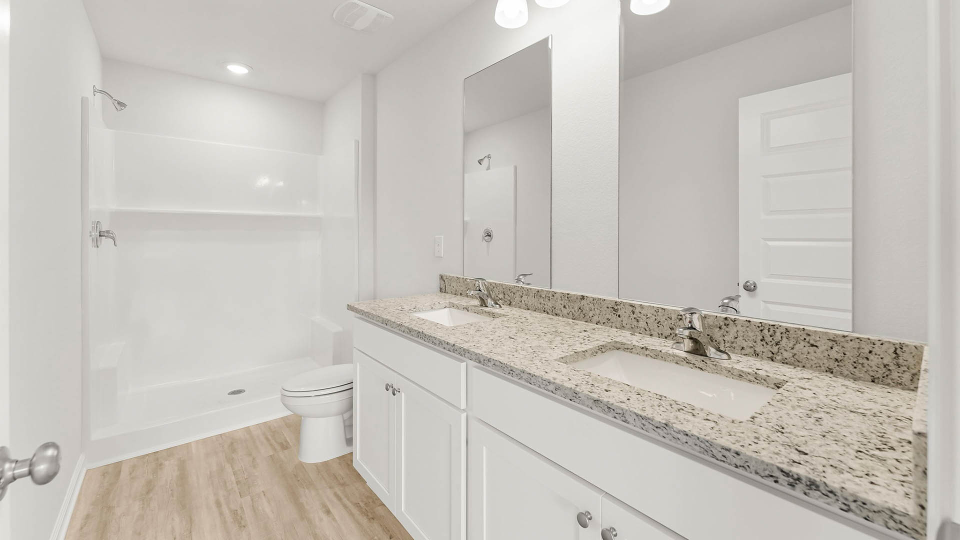 Primary bathroom with double vanity granite countertops and toilet and shower.