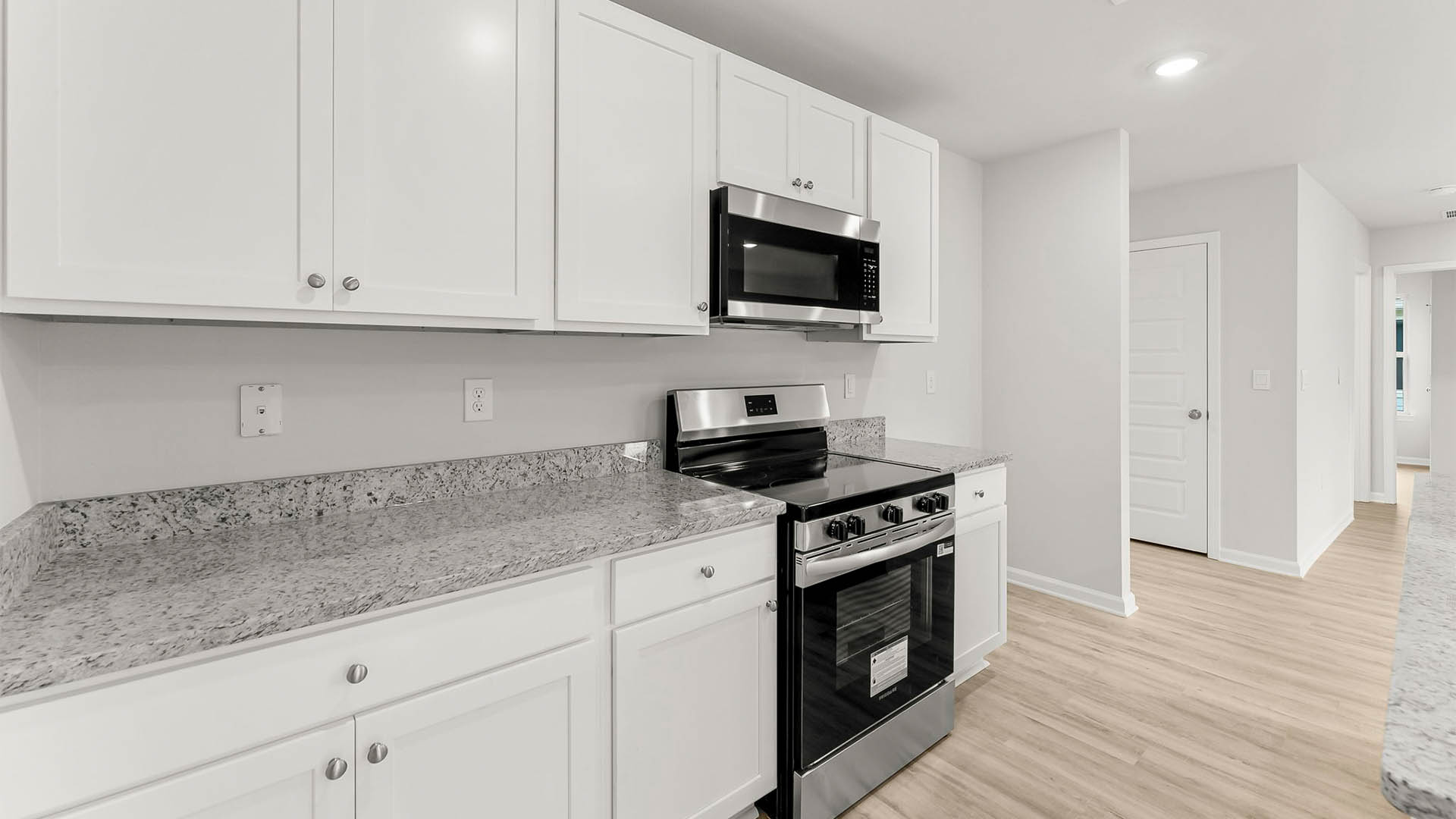 Kitchen with island and granite countertops and stainless-steel appliances and white cabinetry.
