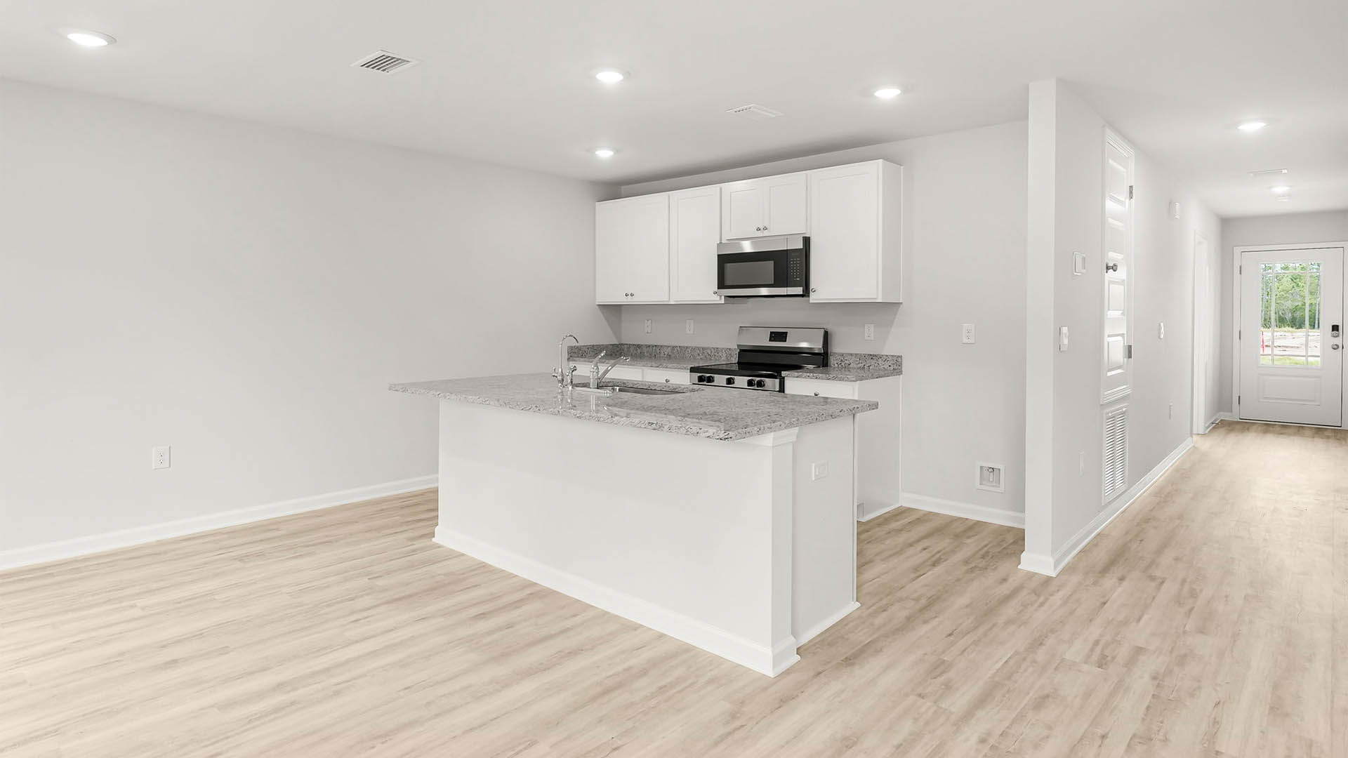 Kitchen with island and granite countertops and stainless-steel appliances and white cabinetry.