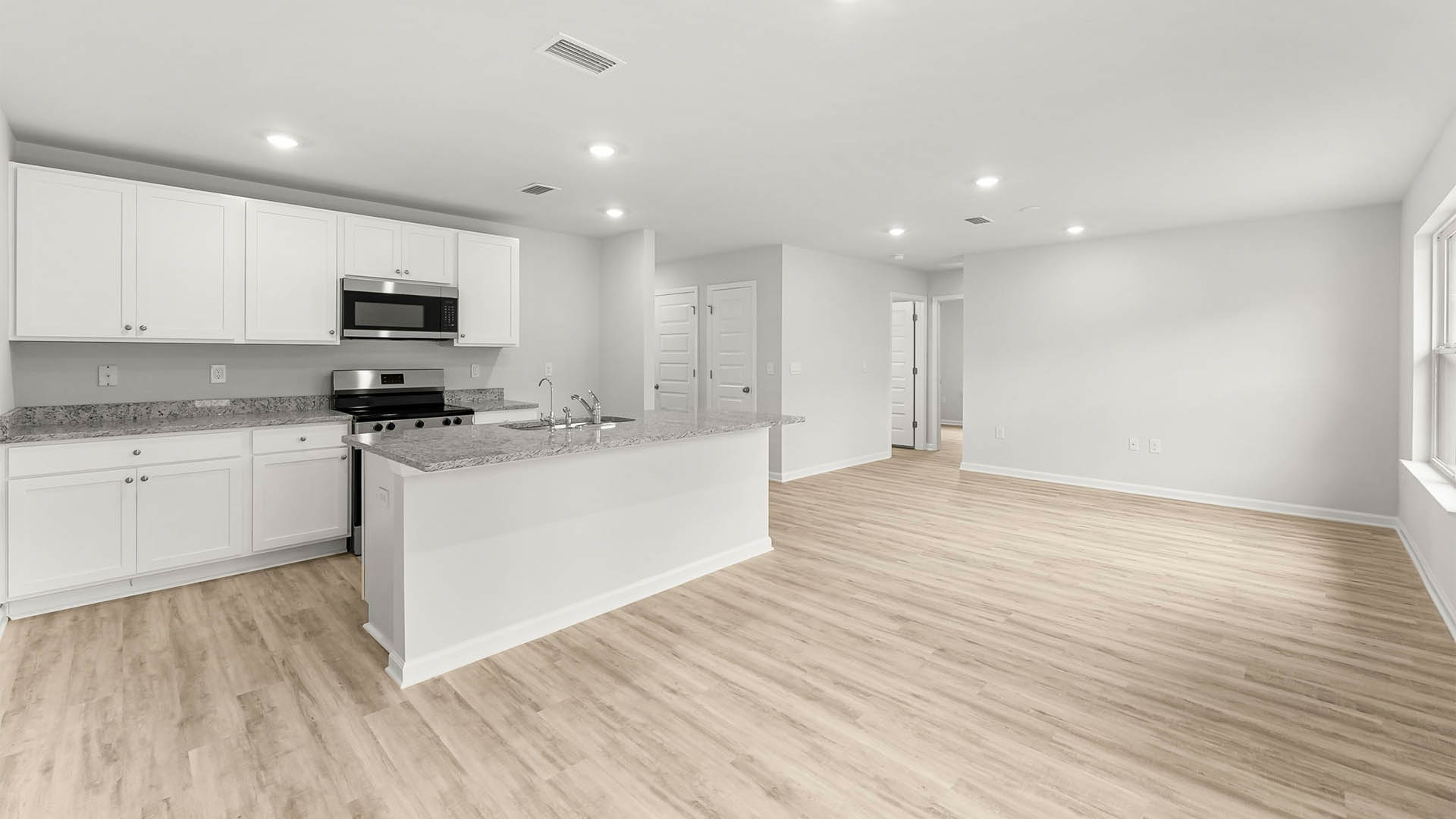Dining area and kitchen next to living room with EVP flooring.