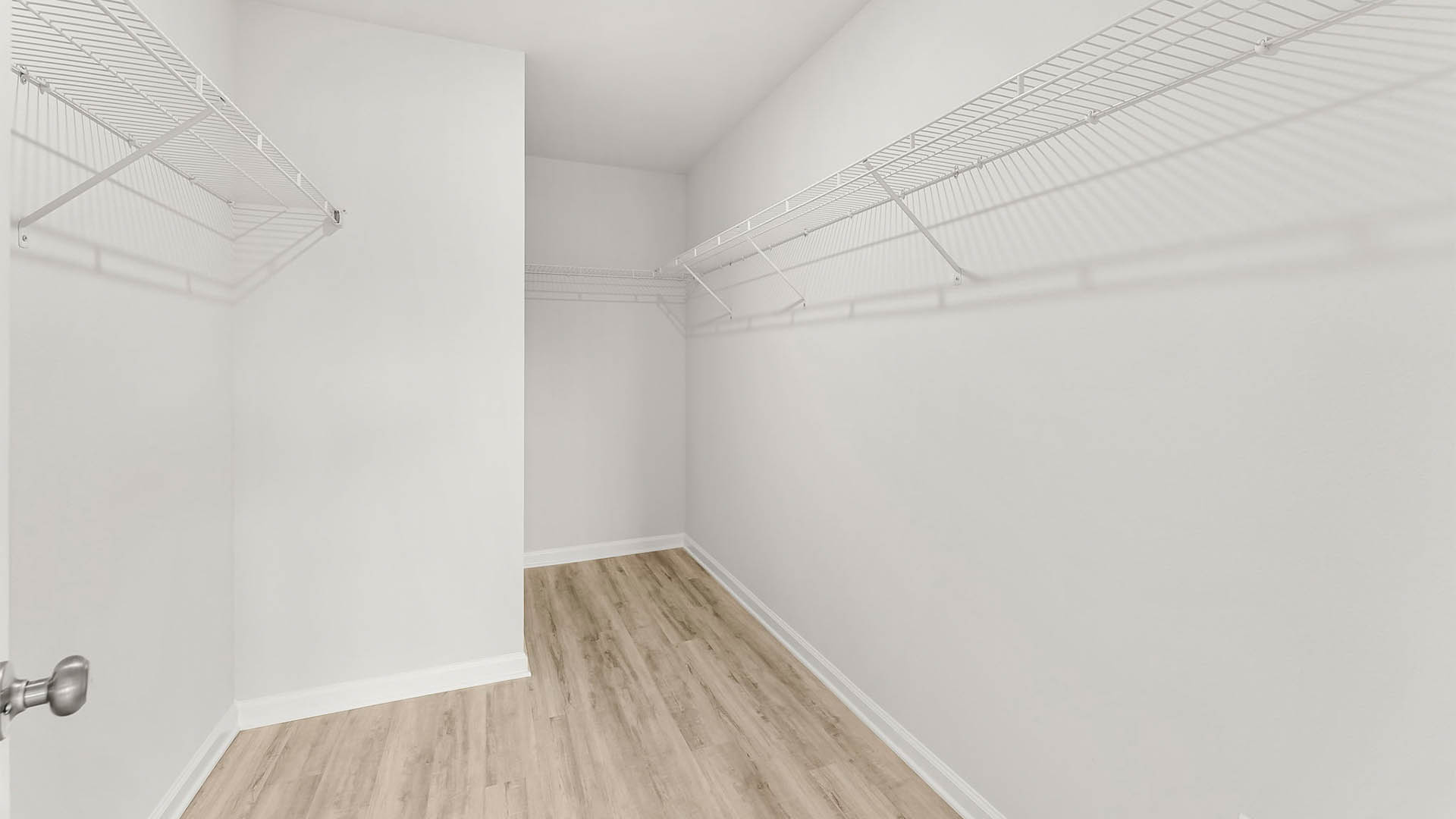 Primary bedroom walk-in closet with EVP flooring and ventilated shelving.