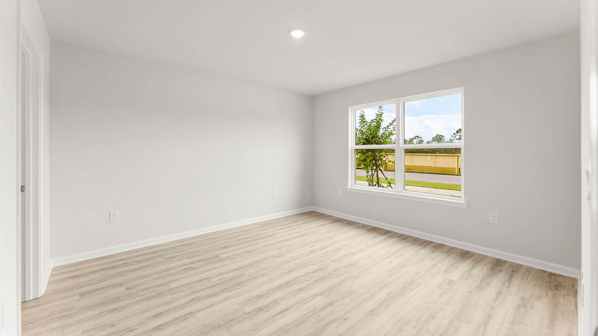 Primary bedroom with EVP flooring and window.