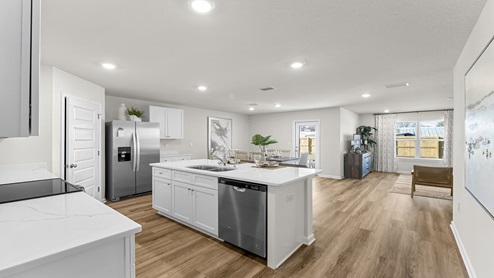 Open kitchen with EVP flooring and white cabinets with kitchen island.
