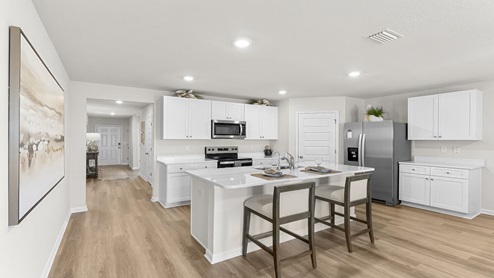 Open kitchen with EVP flooring and white cabinets with kitchen island.