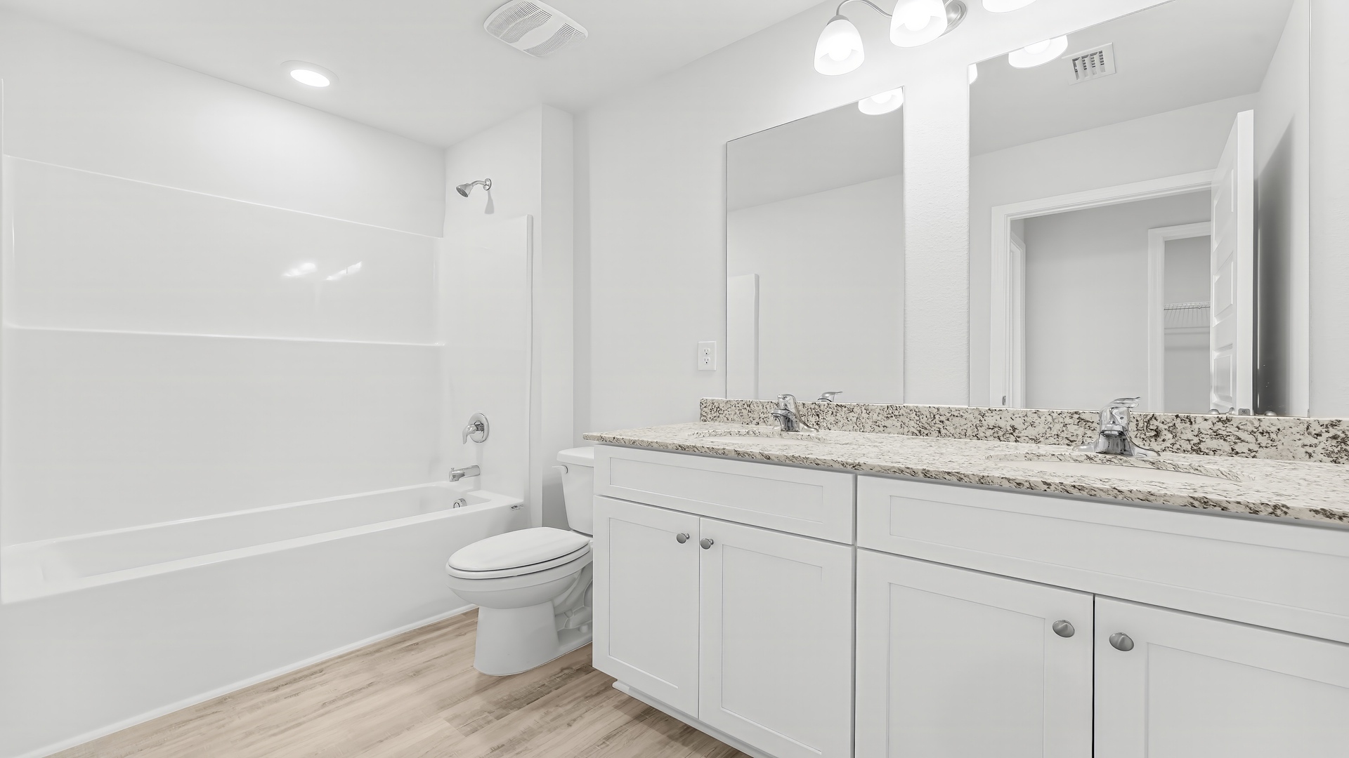 Bathroom with double vanity granite countertops and toilet and combined shower and tub.