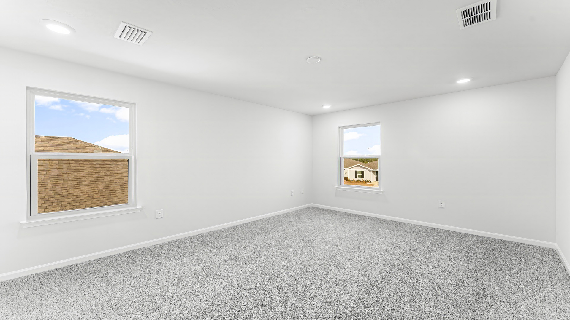 Primary bedroom with carpet floor and two windows.