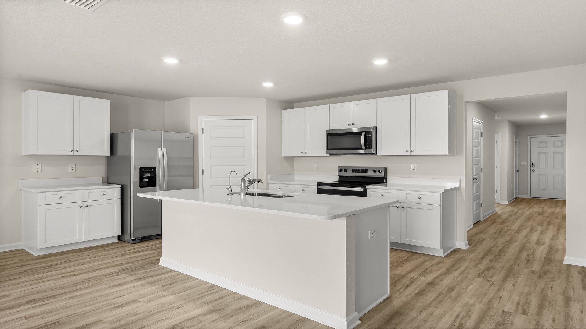 Kitchen island with white cabinets and stainless-steel appliances and quartz countertops and pantry.