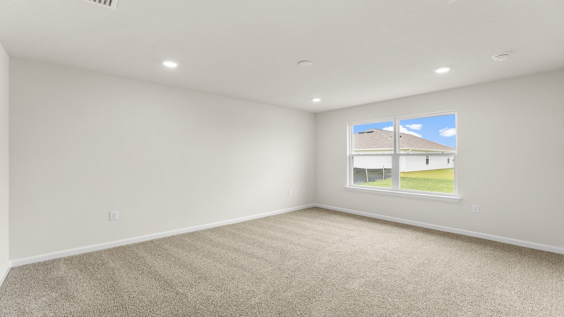 Primary bedroom with carpet floors and window.