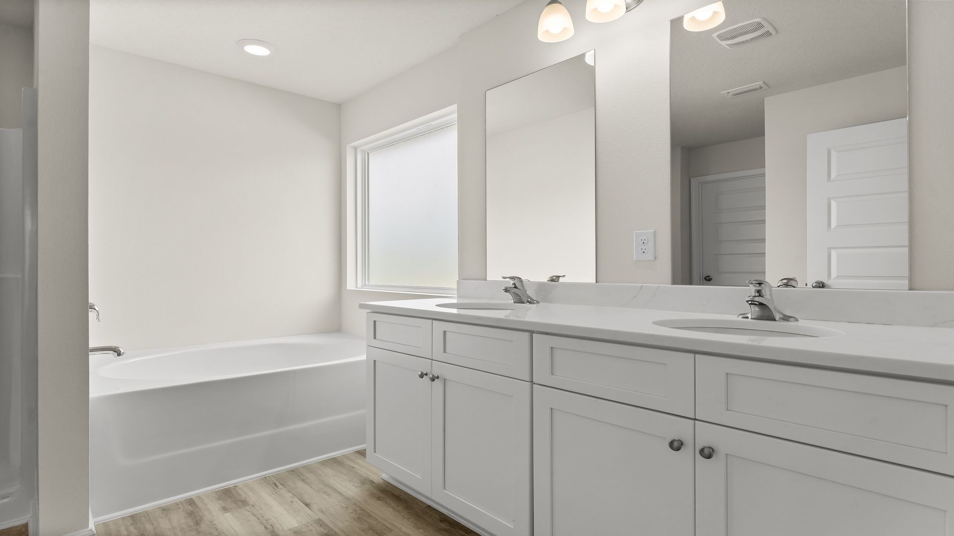Primary bathroom with quartz countertops and double vanity and tub.